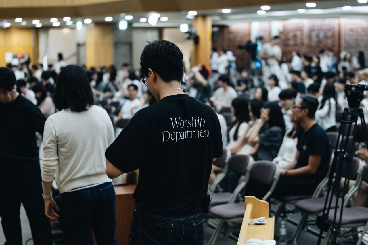 Menus Crowd attending a church service with worship team preparing in the foreground.